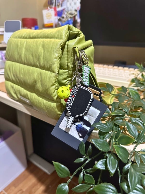 Pickleball paddle keychain on a green bag